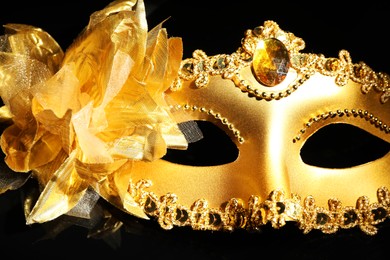 Photo of Beautiful golden carnival mask on black background, closeup