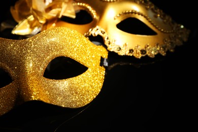 Photo of Beautiful golden carnival masks on black background, closeup