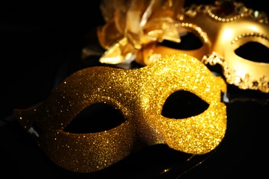 Photo of Beautiful golden carnival masks on black background, closeup