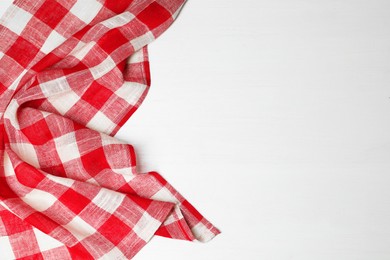 Photo of Crumpled tablecloth with checkered pattern on white wooden table, top view. Space for text