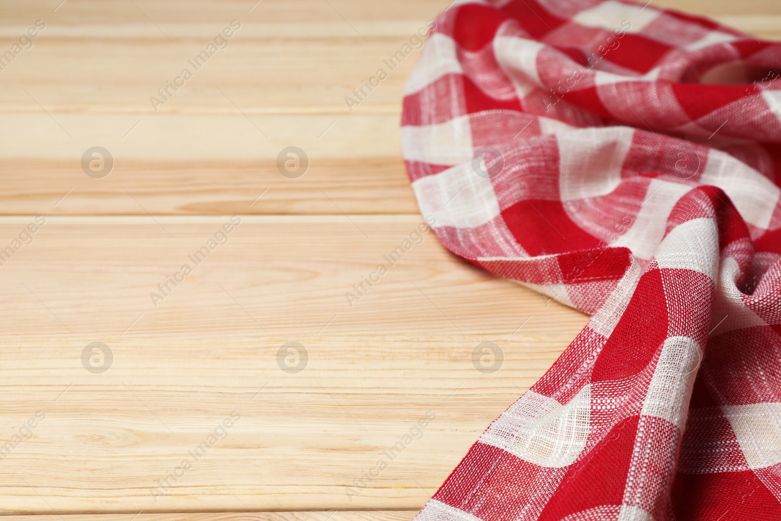 Photo of Crumpled tablecloth with checkered pattern on light wooden table, space for text