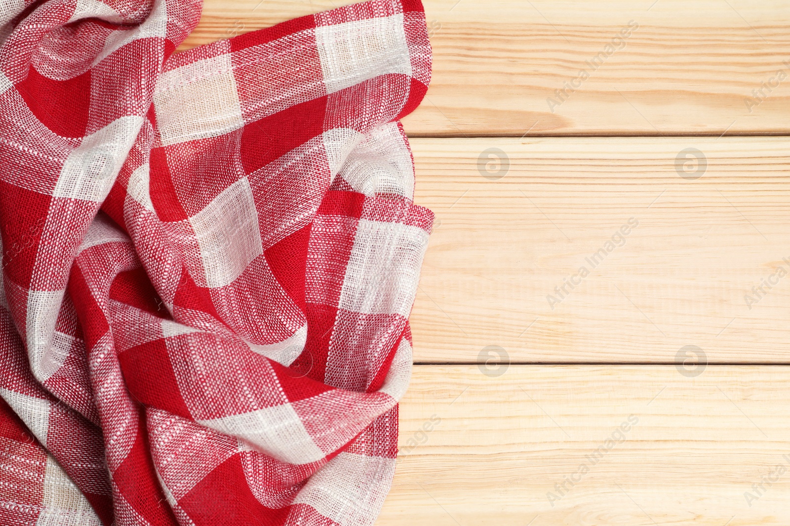 Photo of Crumpled tablecloth with checkered pattern on light wooden table, top view. Space for text