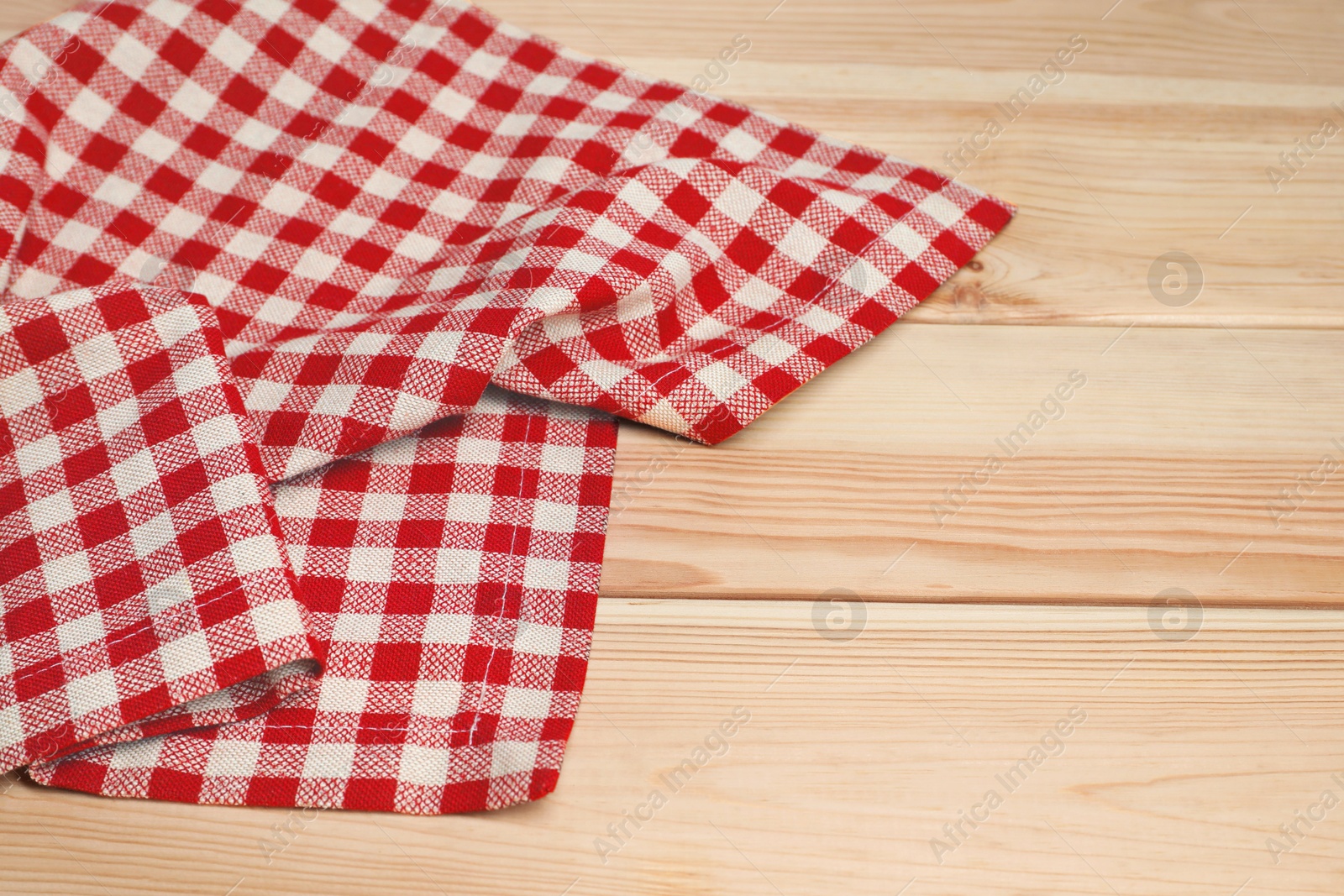 Photo of Crumpled tablecloth with checkered pattern on light wooden table, space for text