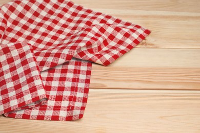 Crumpled tablecloth with checkered pattern on light wooden table, space for text