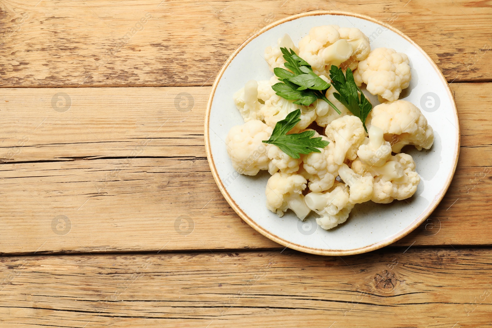 Photo of Tasty cauliflower with parsley on wooden table, top view. Space for text