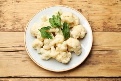 Photo of Tasty cauliflower with parsley on wooden table, top view