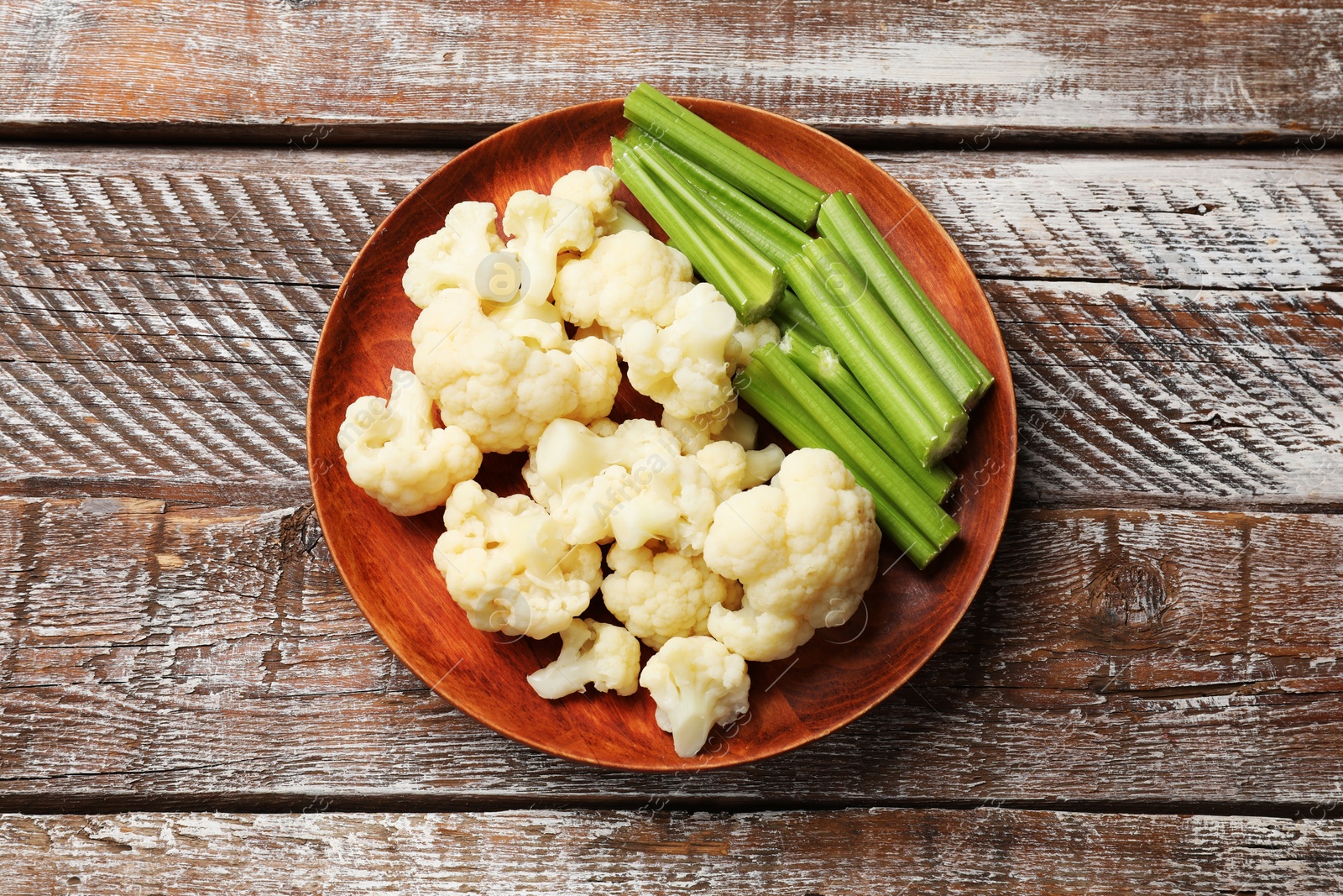 Photo of Tasty cauliflower with celery on wooden table, top view