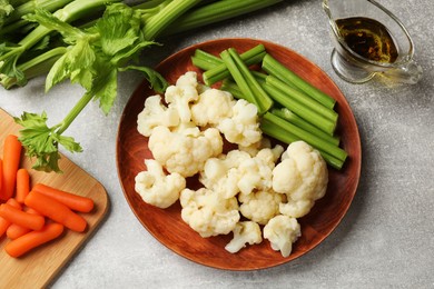 Photo of Tasty cauliflower with celery on grey table, flat lay