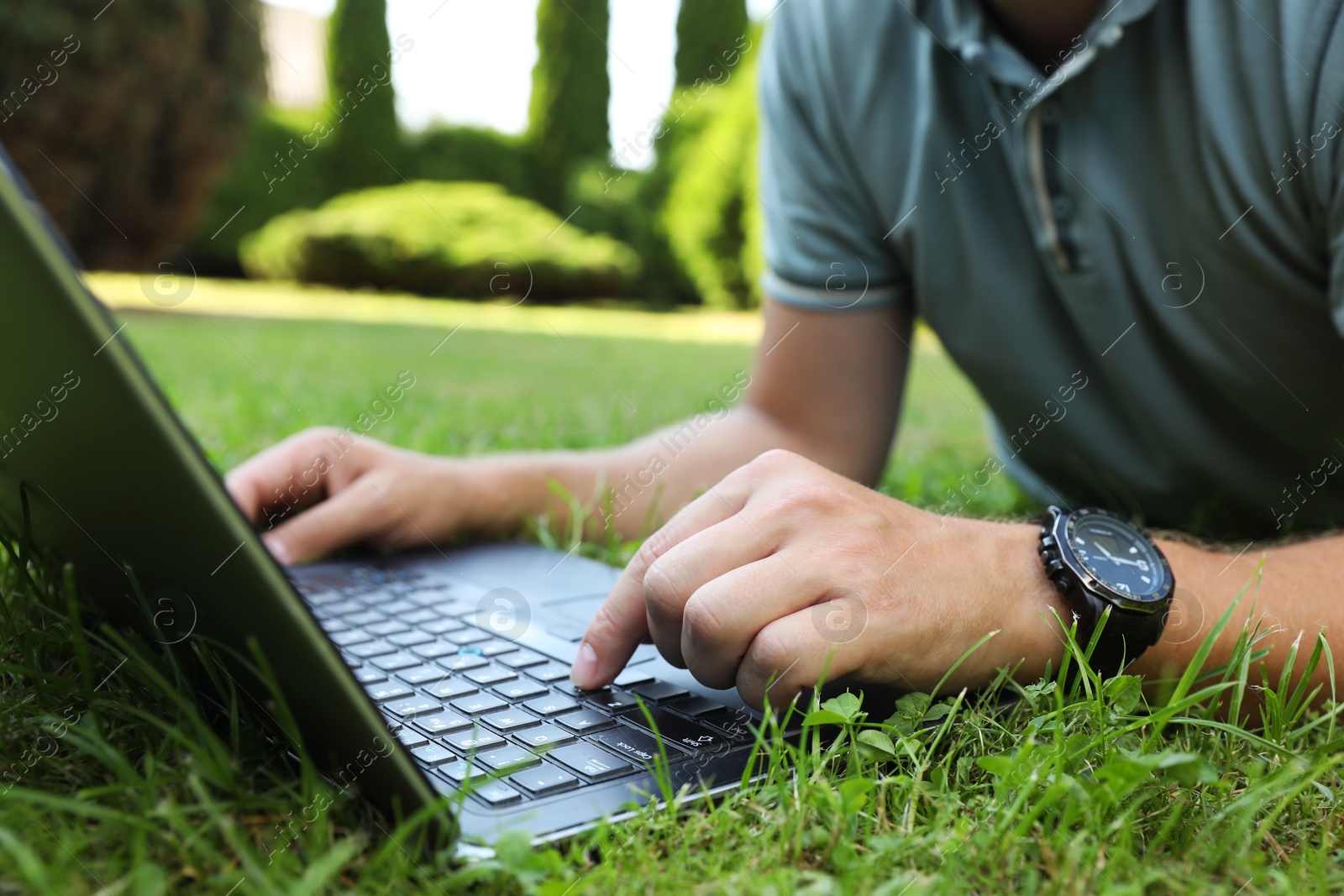 Photo of Man using laptop on green lawn outdoors, closeup