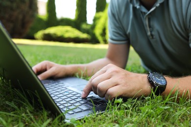 Photo of Man using laptop on green lawn outdoors, closeup