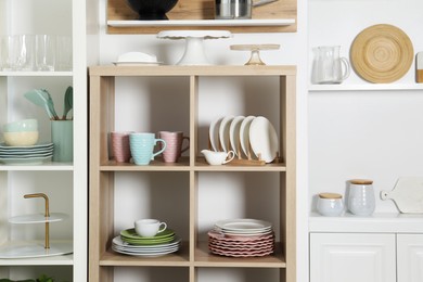 Photo of Shelving units with kitchenware near white wall indoors