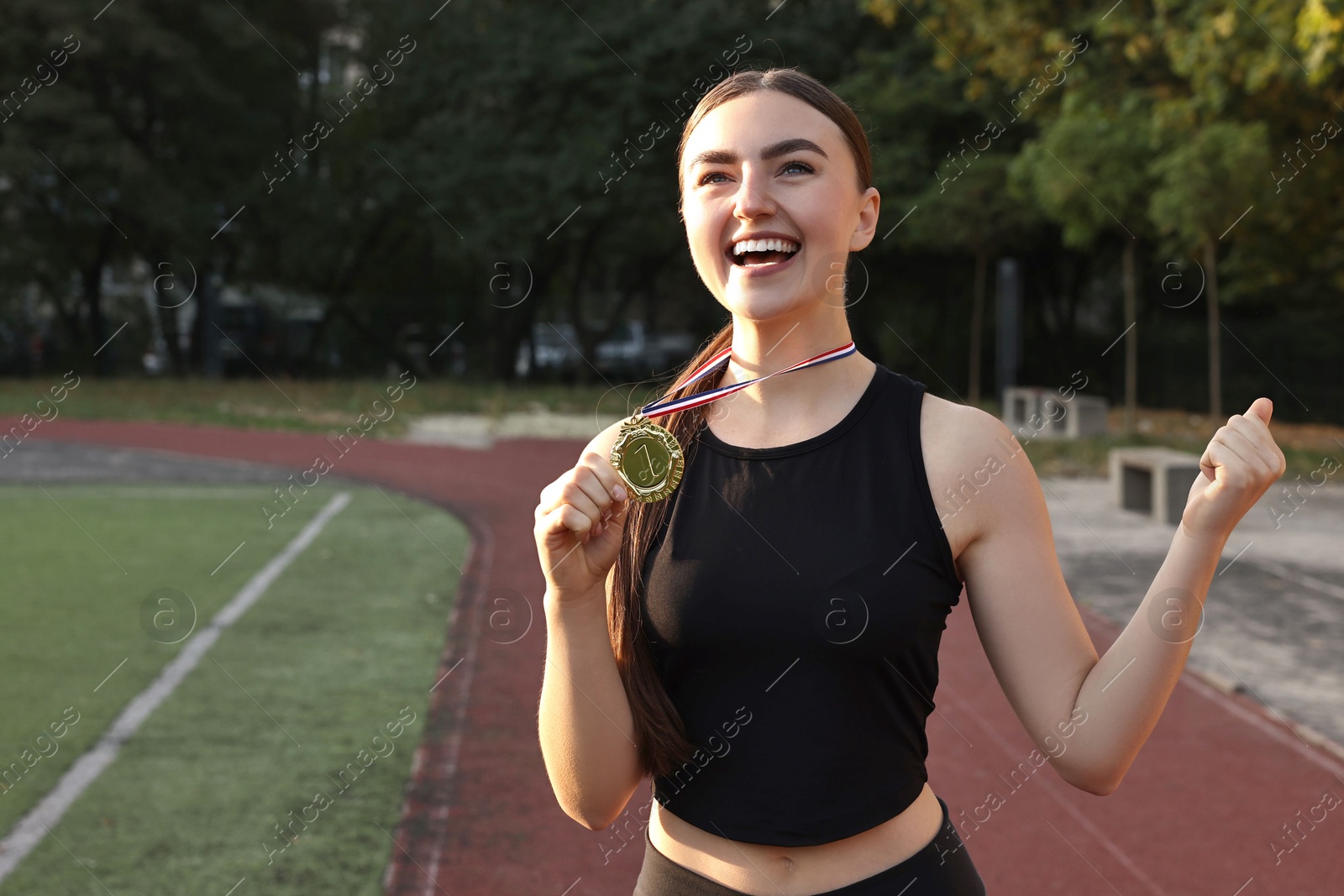 Photo of Happy winner with golden medal at stadium. Space for text