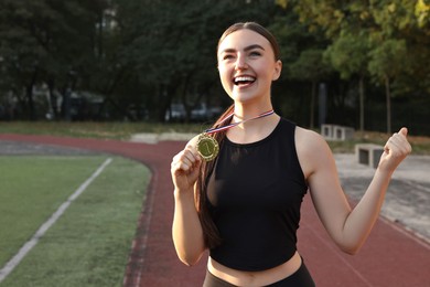 Happy winner with golden medal at stadium. Space for text