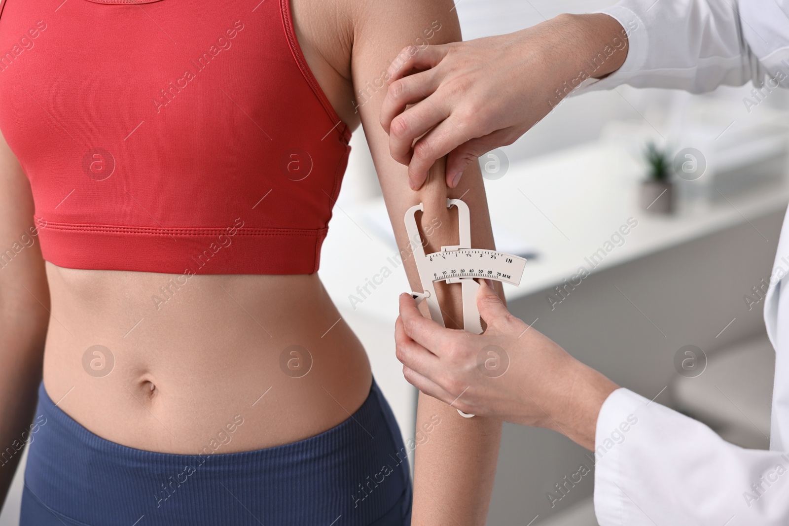 Photo of Doctor measuring woman's body fat with caliper in clinic, closeup