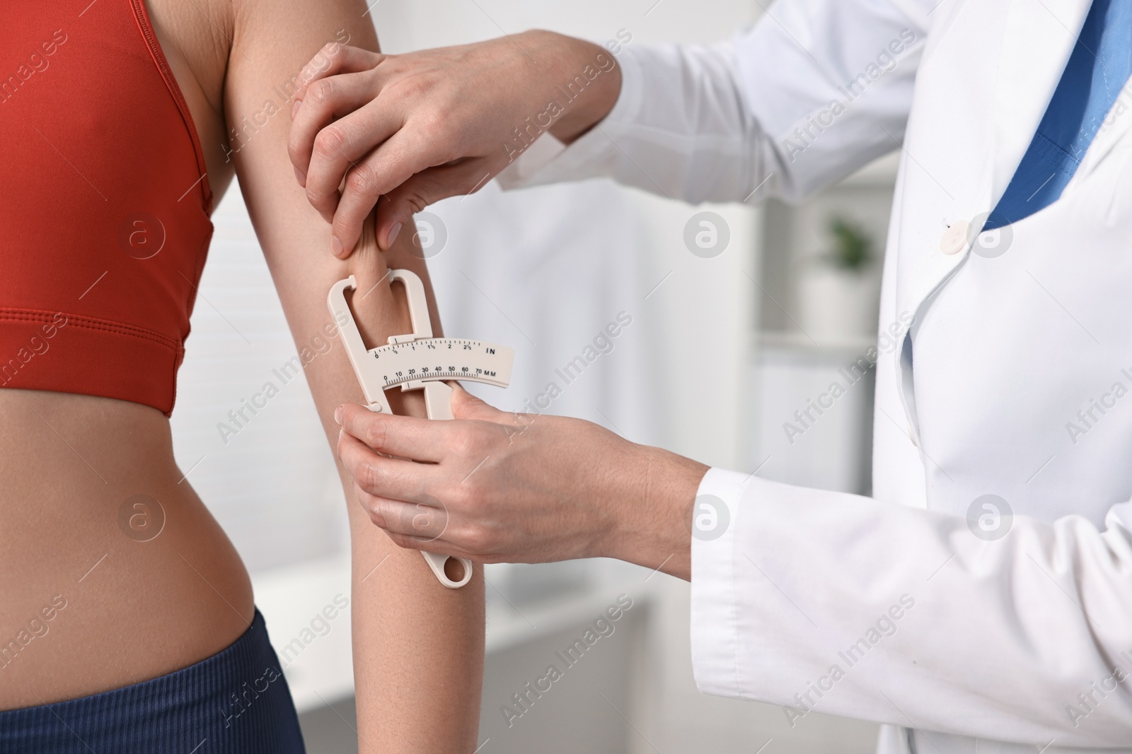 Photo of Doctor measuring woman's body fat with caliper in clinic, closeup