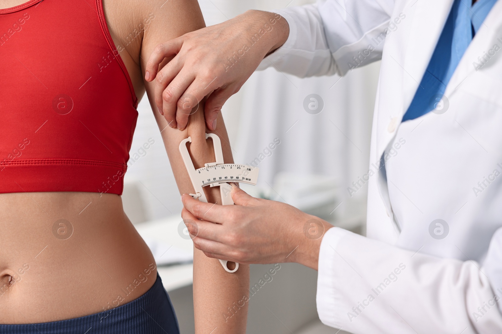 Photo of Doctor measuring woman's body fat with caliper in clinic, closeup