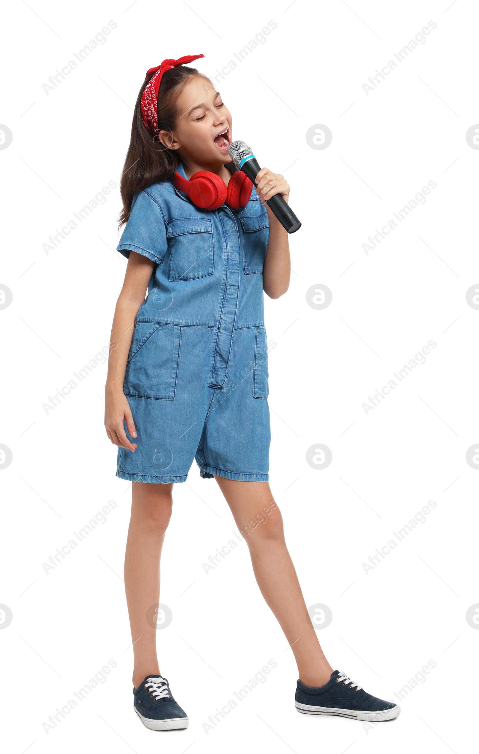 Photo of Girl with headphones and microphone pretending to be singer on white background. Dreaming of future profession