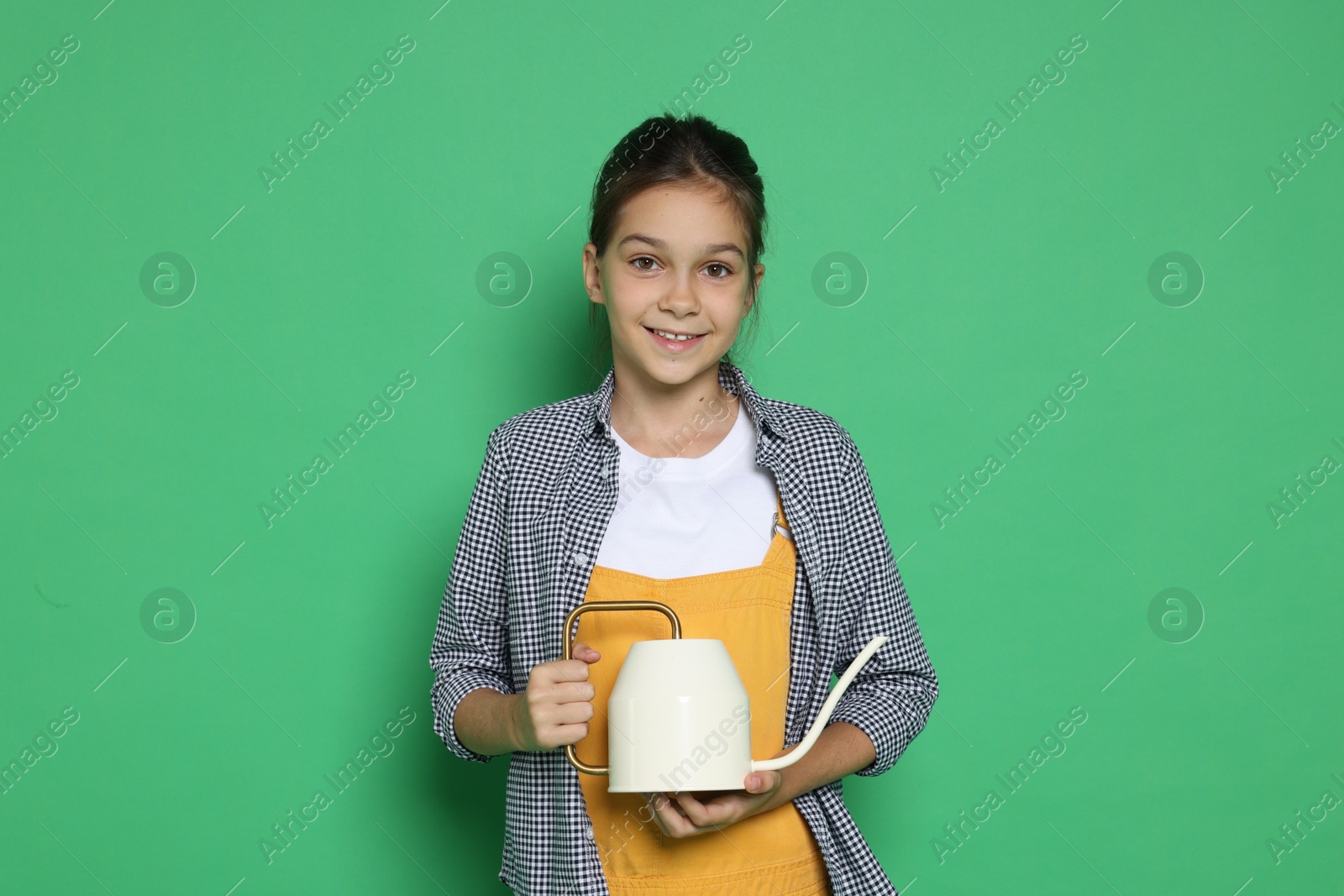 Photo of Girl with watering can pretending to be gardener on green background. Dreaming of future profession