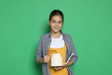 Girl with watering can pretending to be gardener on green background. Dreaming of future profession