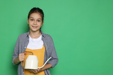 Girl with watering can pretending to be gardener on green background, space for text. Dreaming of future profession