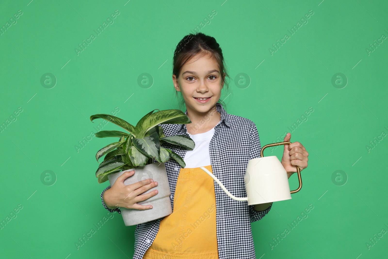 Photo of Girl with watering can and potted plant pretending to be gardener on green background. Dreaming of future profession