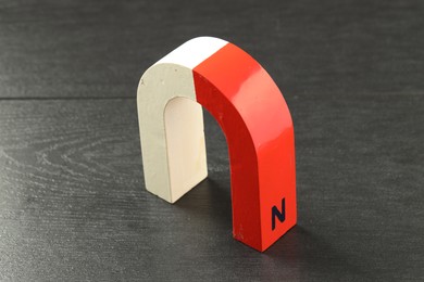 Photo of One horseshoe magnet on black wooden table