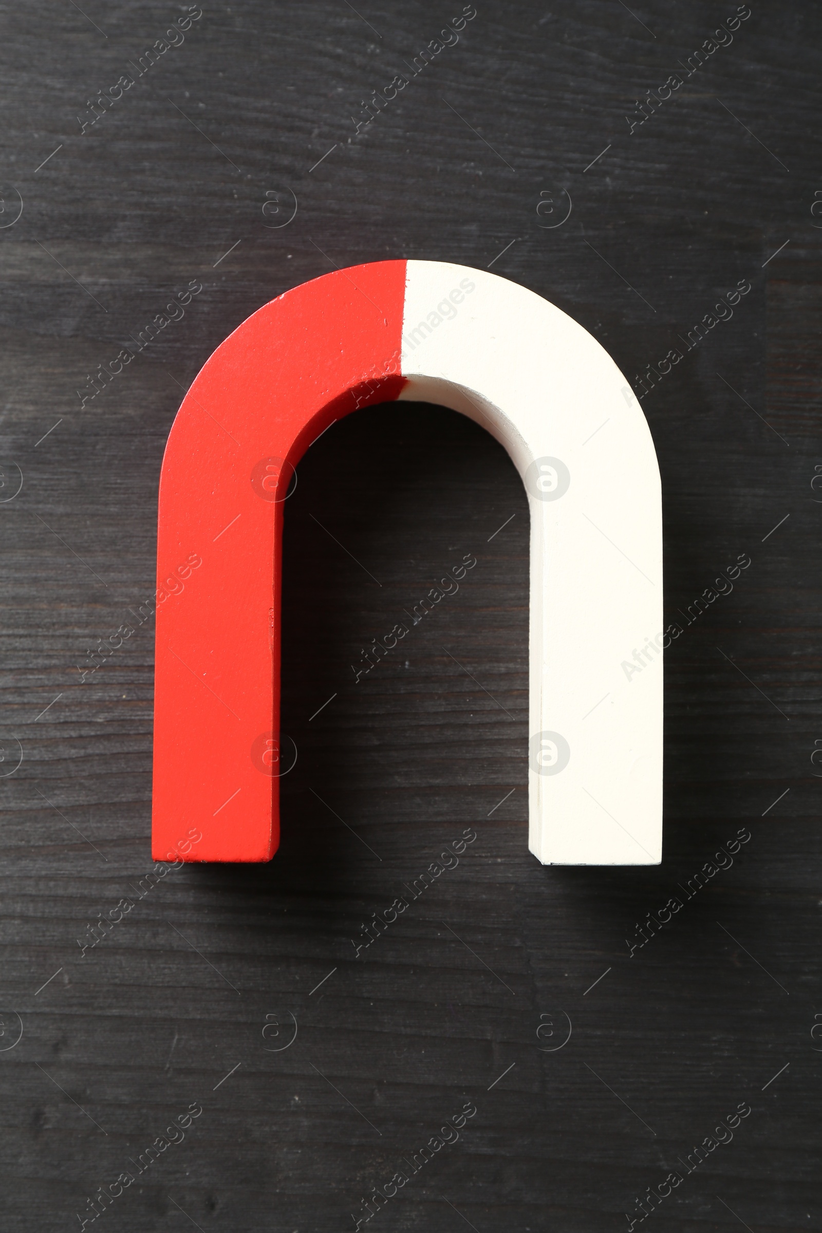 Photo of One horseshoe magnet on black wooden background, top view