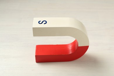 Photo of One horseshoe magnet on white wooden table