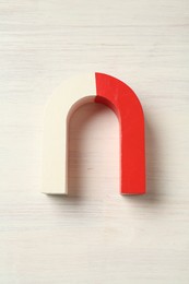 Photo of One horseshoe magnet on white wooden background, top view