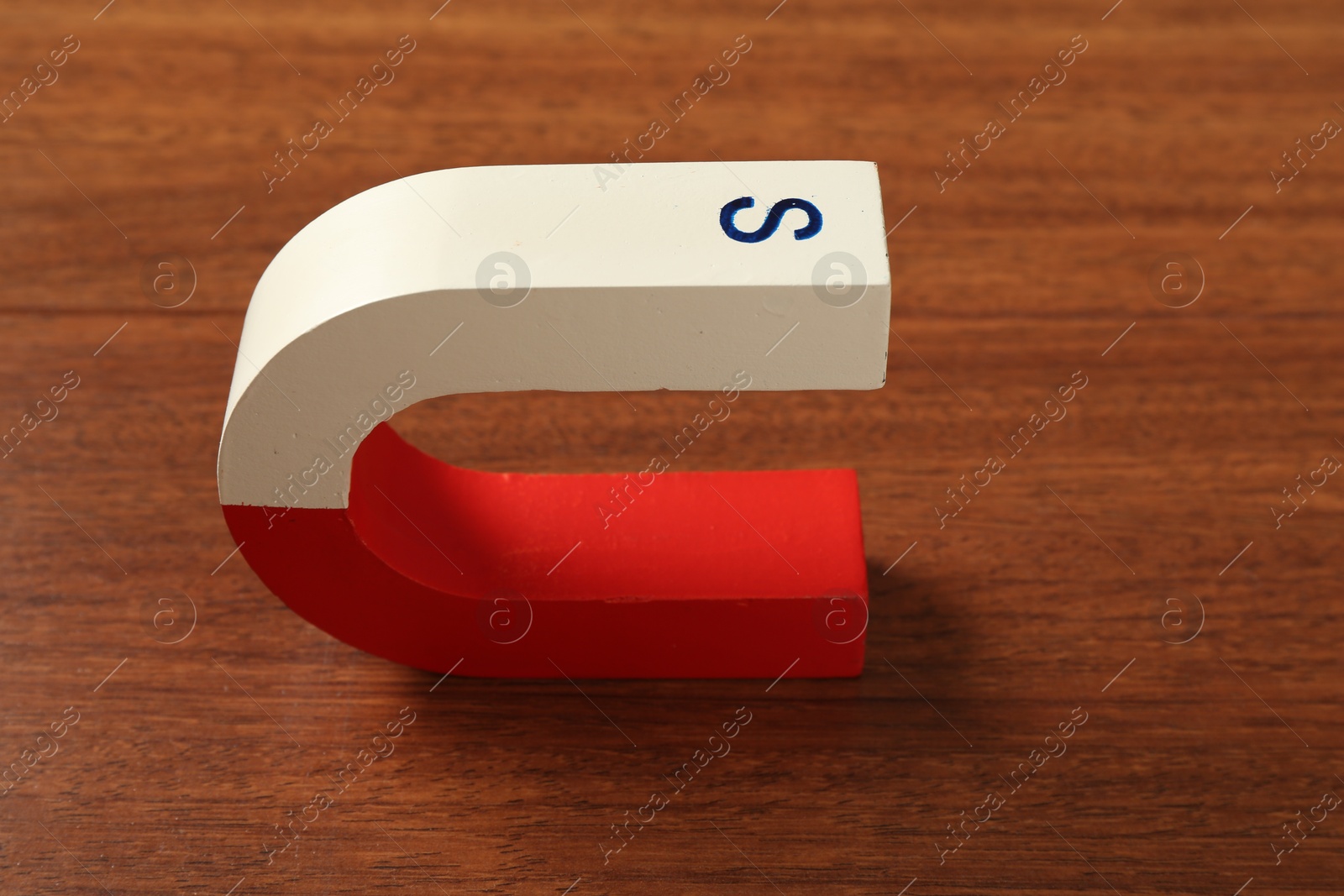 Photo of One color horseshoe magnet on wooden table, closeup