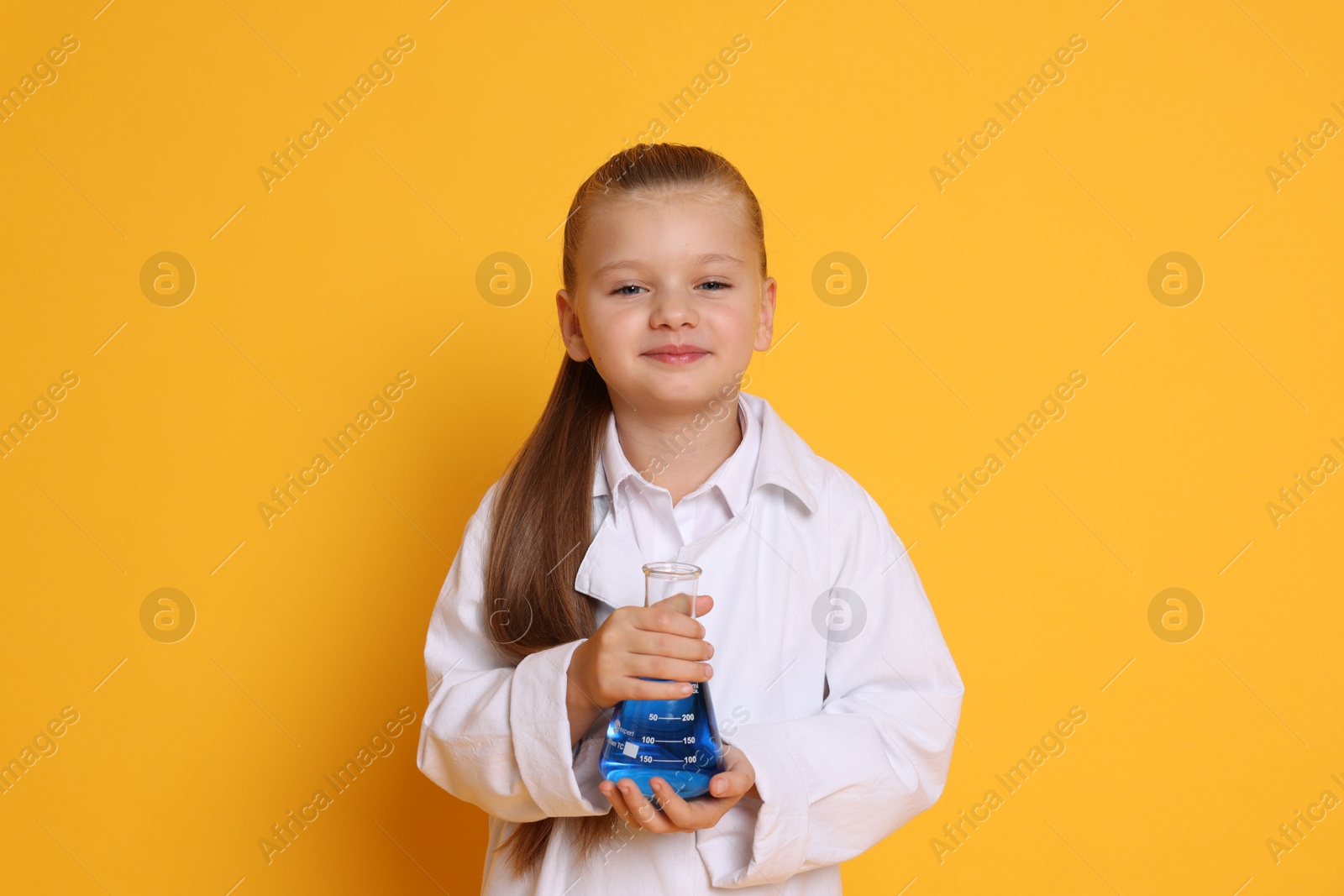 Photo of Little girl with flask pretending to be scientist on orange background. Dreaming of future profession