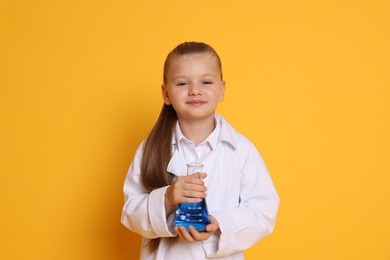 Photo of Little girl with flask pretending to be scientist on orange background. Dreaming of future profession