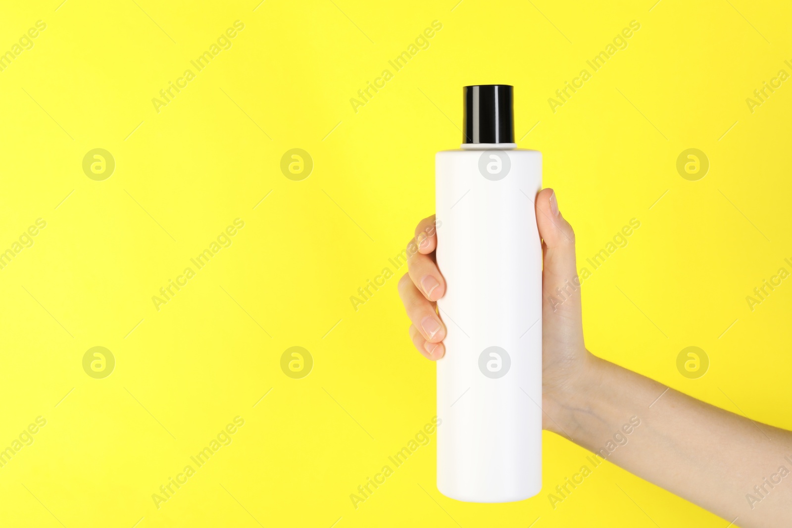 Photo of Woman with shampoo bottle on yellow background, closeup. Space for text