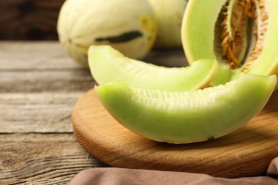 Photo of Fresh cut honeydew melon on wooden table, closeup. Space for text