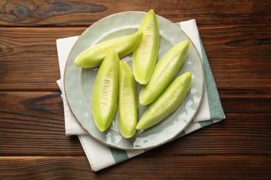 Photo of Fresh cut honeydew melon on wooden table, top view