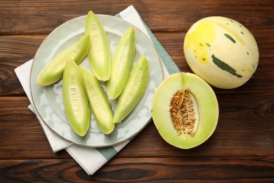 Photo of Fresh whole and cut honeydew melons on wooden table, flat lay