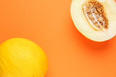 Photo of Whole and half of fresh melon on orange background, flat lay