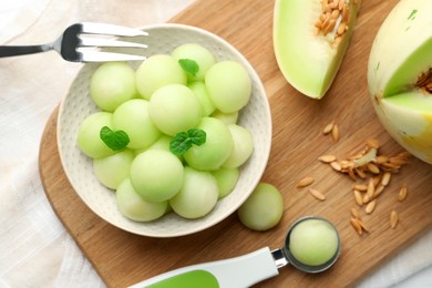 Photo of Melon balls in bowl and fresh fruit on table, top view