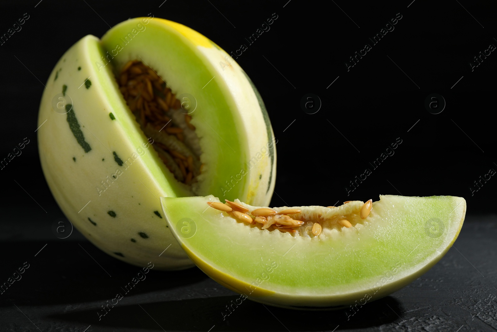 Photo of Fresh ripe honeydew melon on dark table, closeup. Space for text