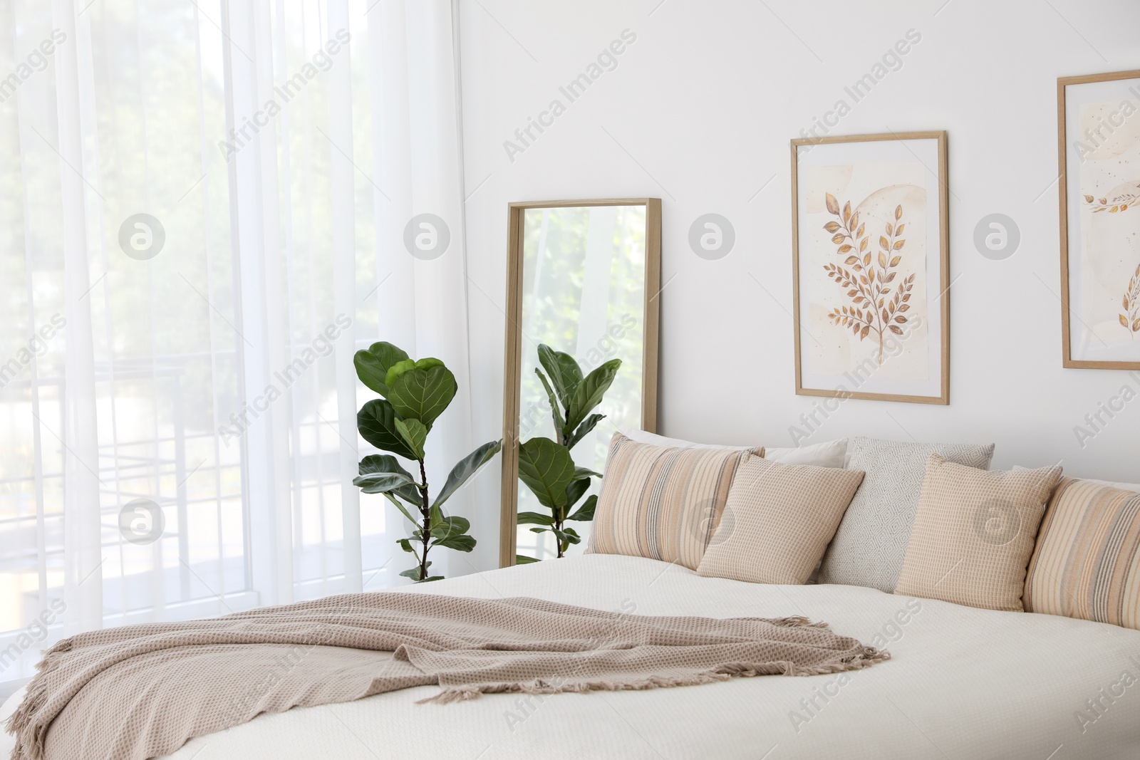 Photo of Large bed, houseplant and full-length mirror near window in room. Stylish bedroom interior