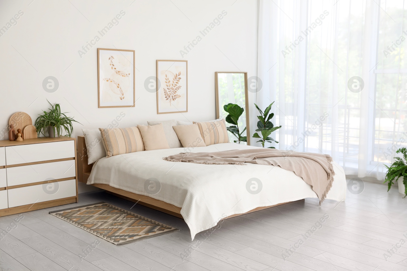 Photo of Large bed, houseplant and full-length mirror near window in room. Stylish bedroom interior