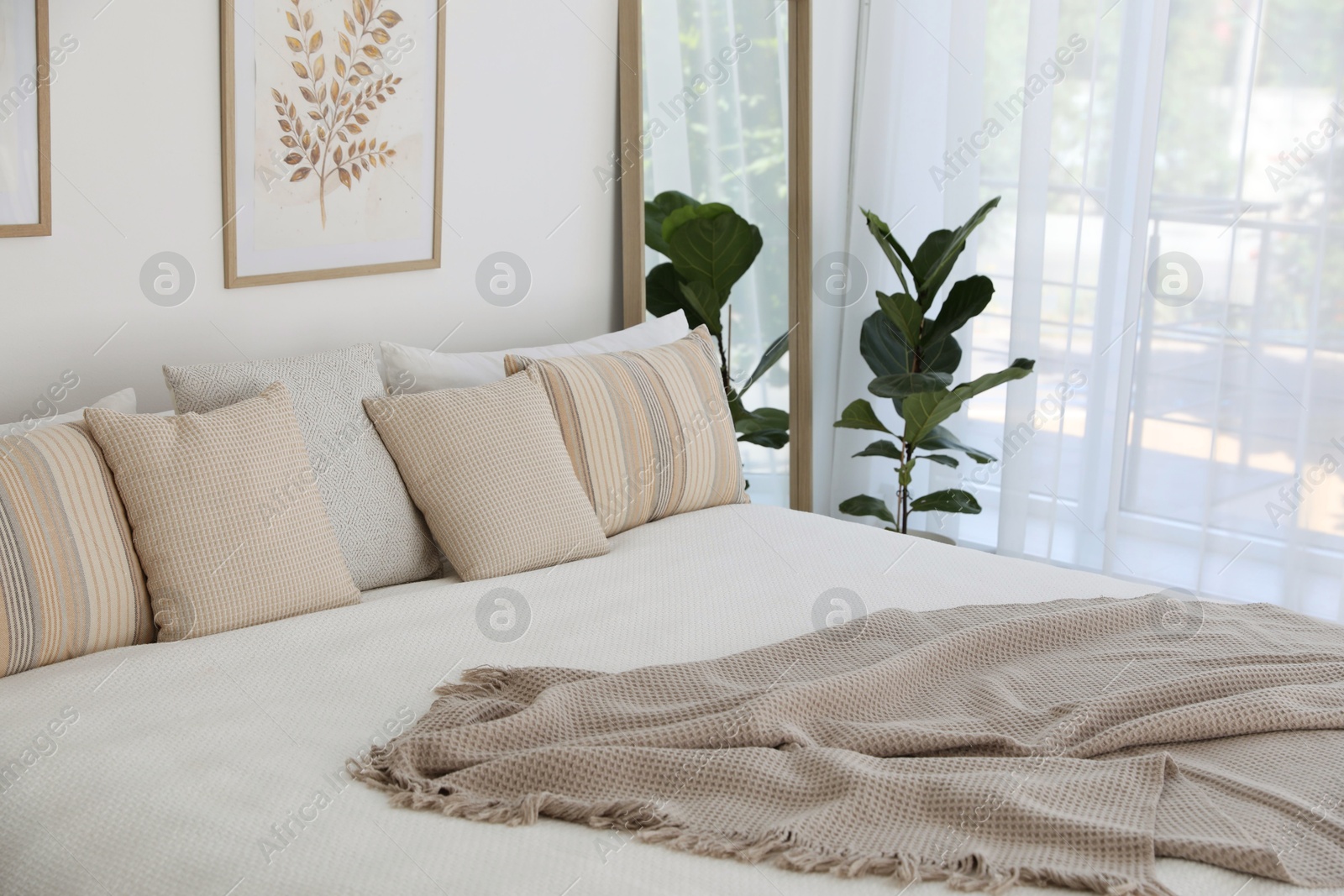 Photo of Large bed, houseplant and full-length mirror near window in room. Stylish bedroom interior