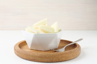 Cut tasty melon in bowl on white table