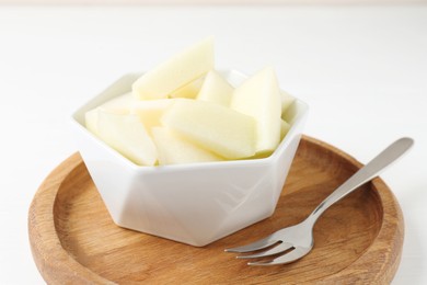 Cut tasty melon in bowl on white table, closeup