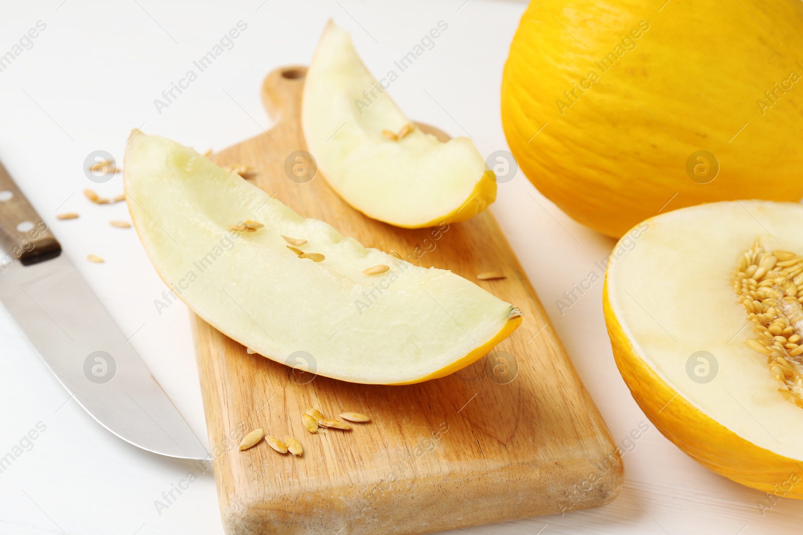 Photo of Fresh ripe melons and knife on white table