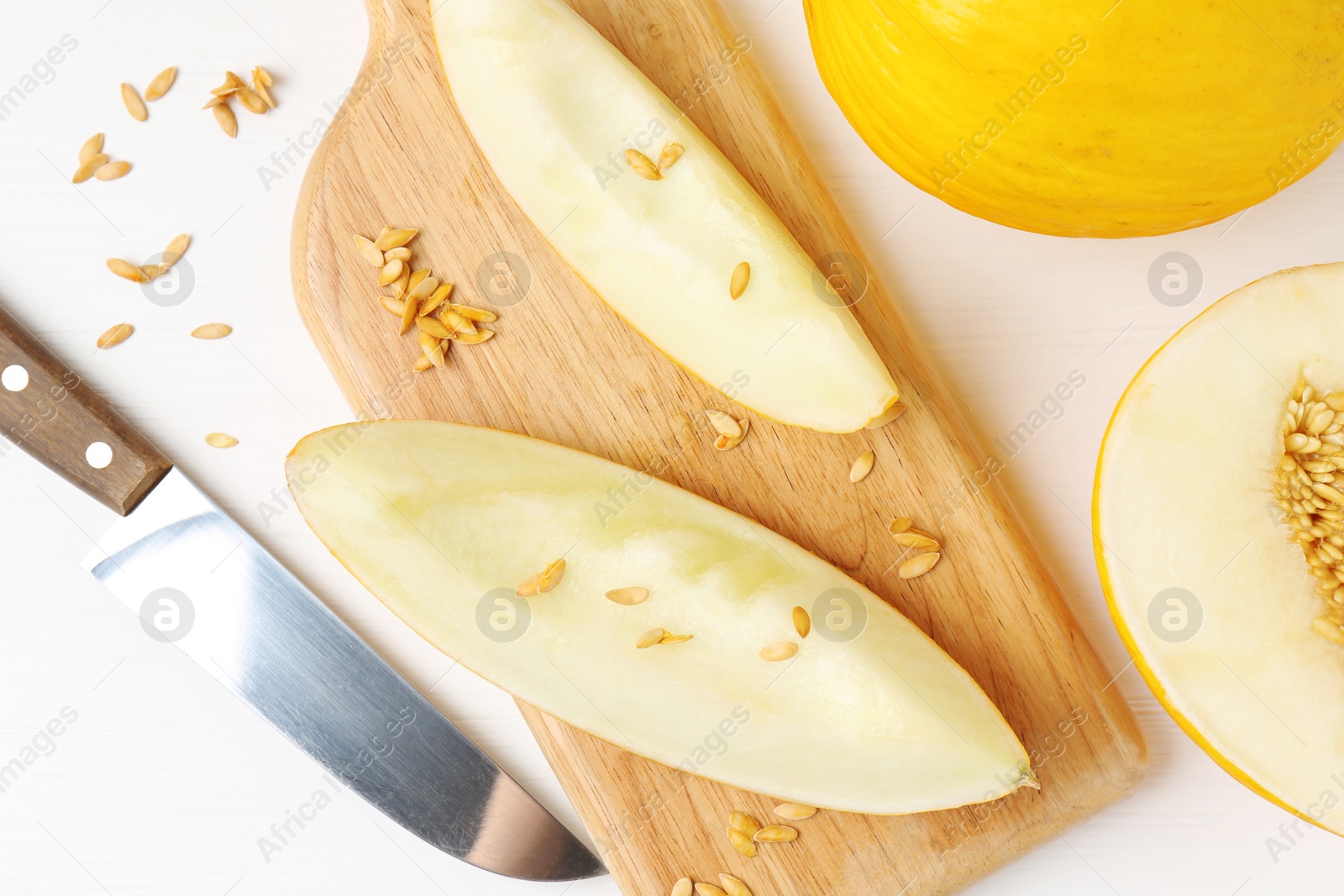 Photo of Fresh ripe melons and knife on white wooden table, flat lay