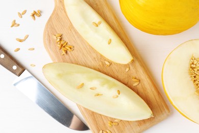 Photo of Fresh ripe melons and knife on white wooden table, flat lay