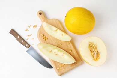 Fresh ripe melons and knife on white wooden table, flat lay