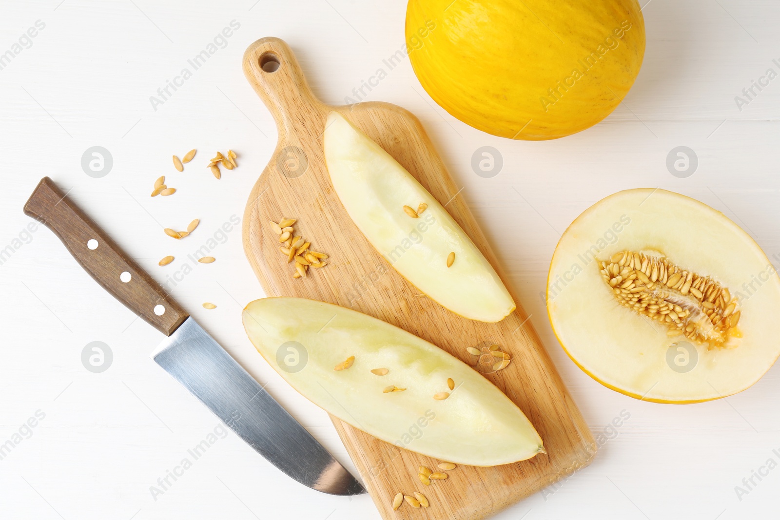 Photo of Fresh ripe melons and knife on white wooden table, flat lay