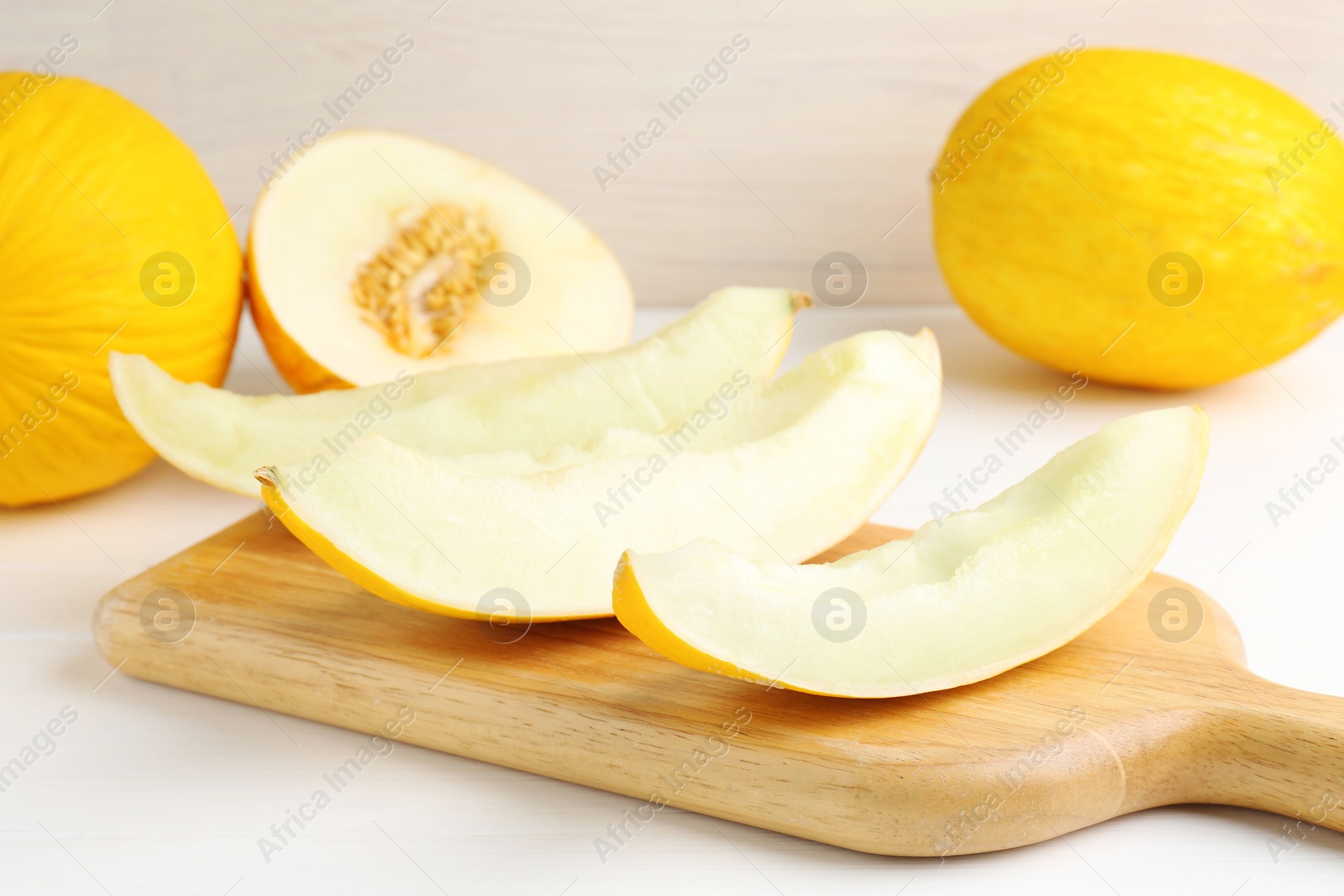 Photo of Whole and cut ripe melons on white table